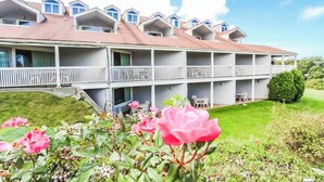 A multi-story hotel with balconies and a well-maintained lawn. - Deluxe 1BR Condo w/ Jacuzzi & Bay Views (Newport)