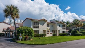 A residential building with a flat roof, multiple balconies, and a well-maintained lawn. - Beachside Rental w/ Balcony & Pool (Boca Raton)