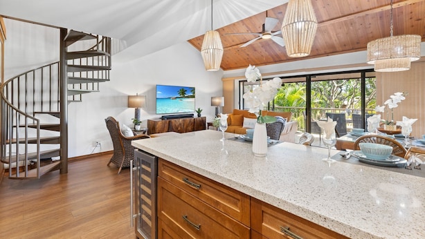 Una cocina amplia con una isla grande, piso de madera y una escalera moderna.