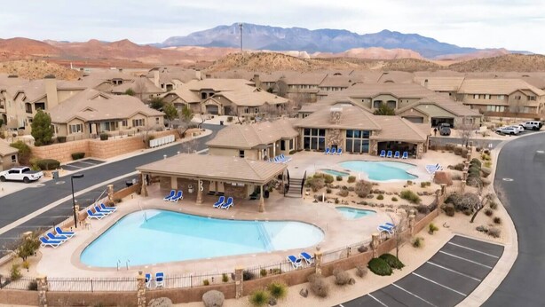 Un complexe hôtelier doté de plusieurs piscines, d’un espace couvert avec des chaises longues et offrant une vue sur le paysage désertique environnant.