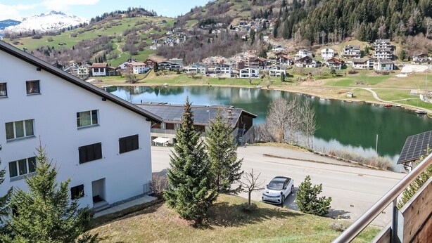 A residential area with houses, a lake, and a mountain in the background. - La Prada Wohnung 119 by Interhome (Laax)