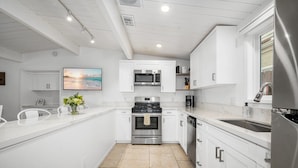 A modern kitchen with white cabinetry, stainless steel appliances, and a tiled floor.