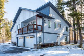 Une maison à deux étages avec un balcon, un garage et des fondations en pierre.