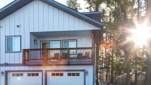 A two-story house with a balcony, two garages, and a snowy landscape. - New! Home located off Flathead River with balcony & fireplace (Columbia Falls)