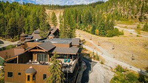 Eine Lodge mit mehreren Holzhäusern, einer Seilbahn und einem Bergpanorama.