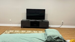 Un dormitorio moderno con una cama, un televisor sobre un mueble bajo y piso de madera.