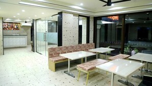 Un restaurant avec des banquettes et des tables, un ventilateur de plafond et une cloison en verre donnant sur la rue.