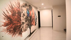 Un couloir orné d’une grande fresque murale représentant un arbre et des motifs abstraits.