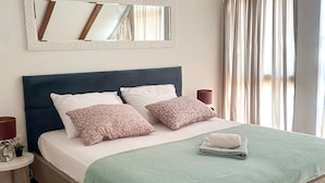 A neatly made bed with a green blanket and two patterned pillows, a bedside table with a lamp, and a mirror above the bed. - Pet friendly home in Durdevac (Durdevac)