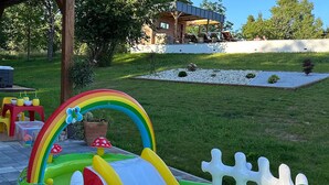 A children's play area with a rainbow slide and inflatable pool, surrounded by a well-maintained lawn and a small garden. - Pet friendly home in Durdevac (Durdevac)