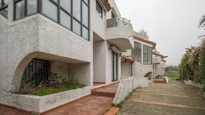 Um edifício moderno com fachada branca, janelas amplas e um caminho de tijolos que leva à entrada.