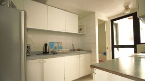 Uma cozinha com armários brancos, uma pia e uma geladeira.