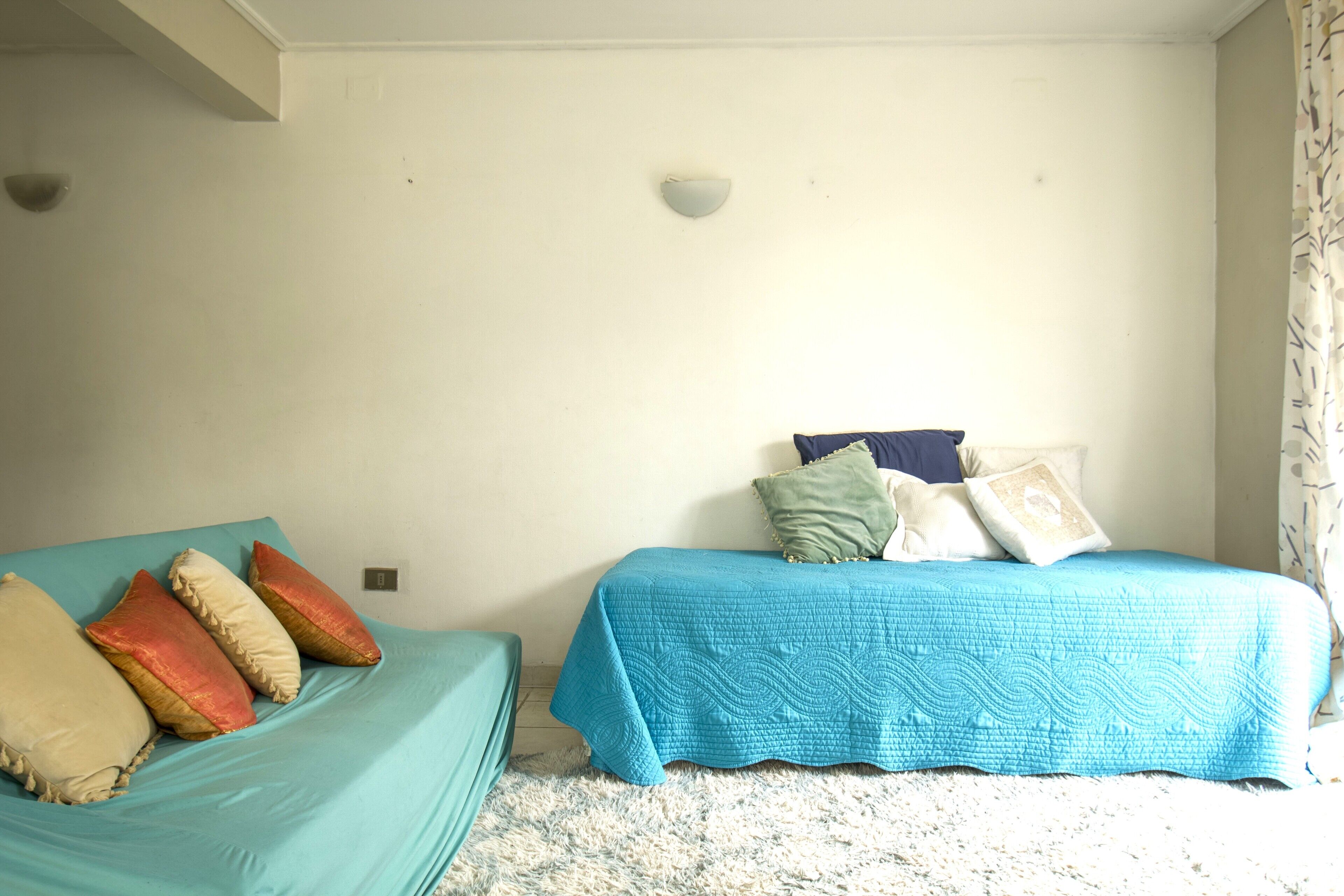 Ein Schlafzimmer mit zwei Betten, jeweils mit blauer Bettdecke und vielen Kissen.