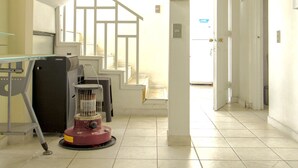 Corredor de hotel com escada, escrivaninha e aspirador de pó.