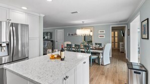A modern kitchen with a marble countertop, stainless steel appliances, and a dining area with a chandelier.