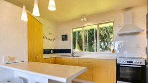 A kitchen with a central island, a stove, and a window with a view of trees.