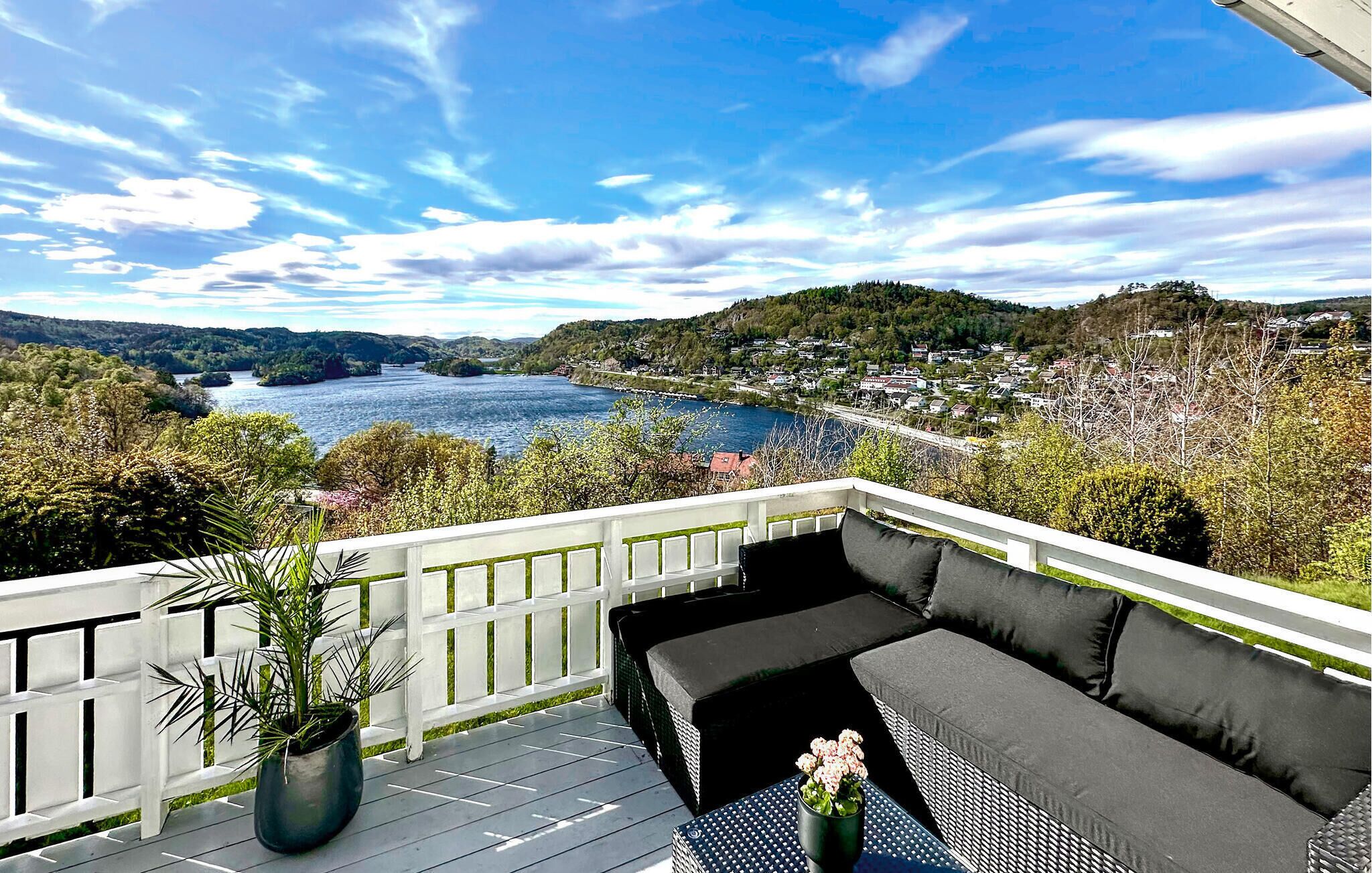 Un balcon avec un canapé et une table, donnant sur une rivière et une ville.