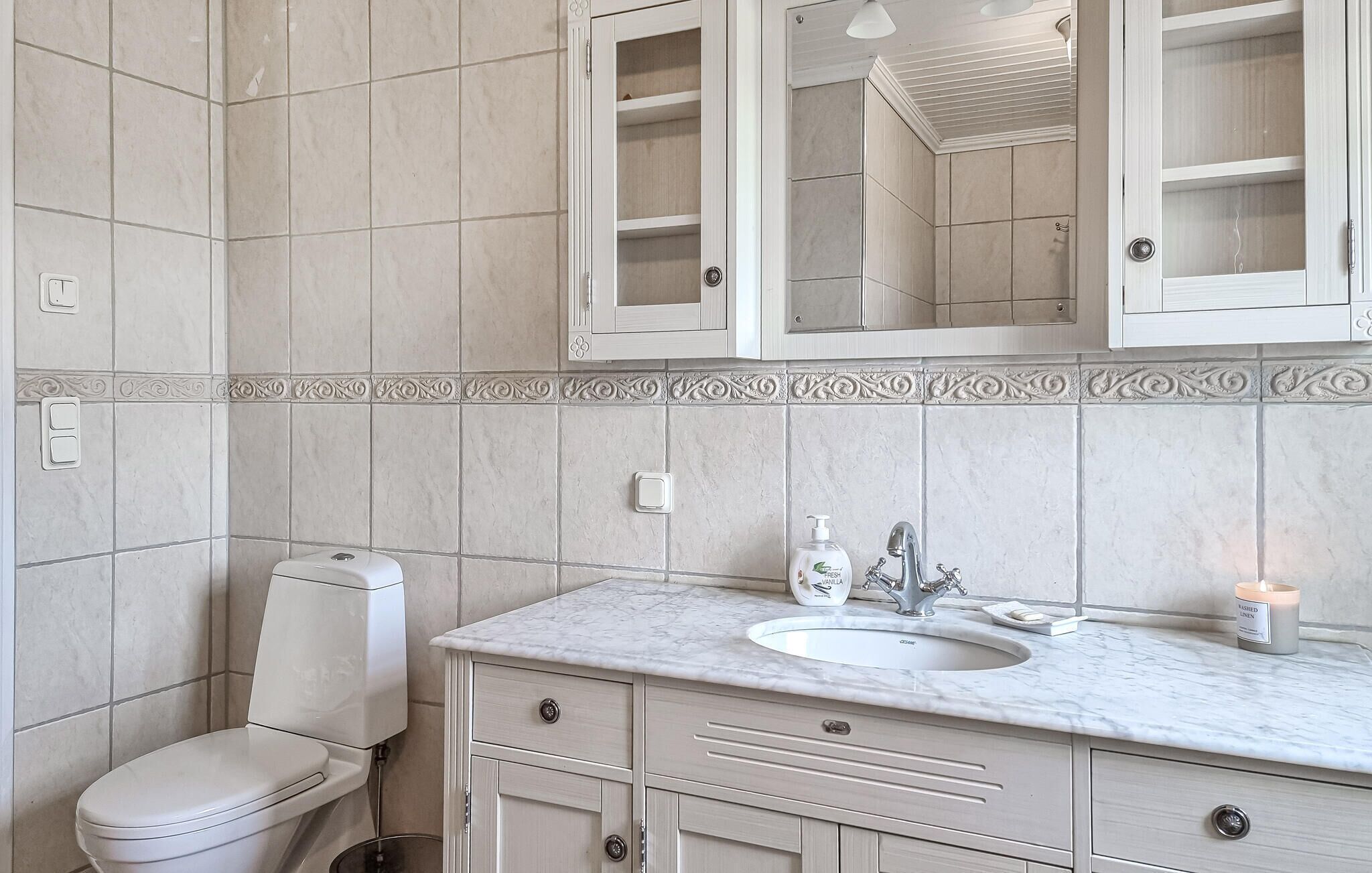 A bathroom with a toilet, a sink, and a mirror.