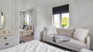 Quarto com cama, sofá, janela com vista e espelho.