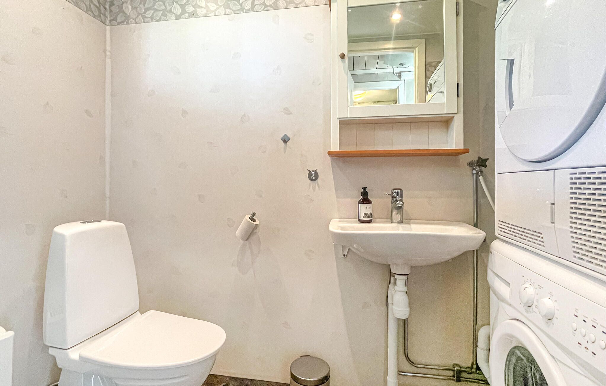 A bathroom with a toilet, sink, and washing machine.