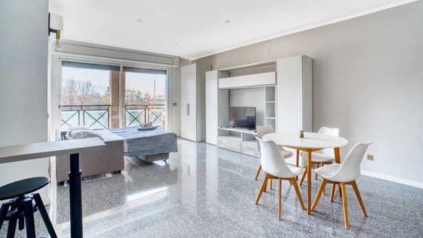 A modern room with a bed, a dining table with chairs, a TV, and a balcony with a view. - GuestHost - Casa Frida, apartement with balcony (Foligno)