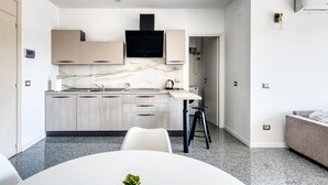 A modern kitchen with marble backsplash, built-in appliances, and a dining area with a round table. - GuestHost - Casa Frida, apartement with balcony (Foligno)
