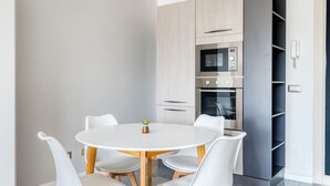 A modern kitchen with a round table and white chairs, built-in appliances, and a grey cabinet. - GuestHost - Casa Frida, apartement with balcony (Foligno)