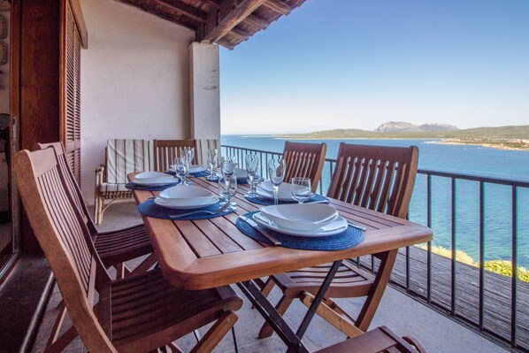 A wooden table set for four with a view of the sea.