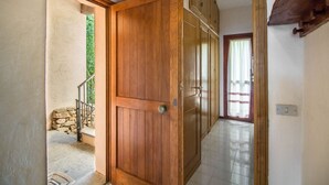 A wooden door leading to a room with a tiled floor and a stone wall outside. - GuestHost - Dreamy Sea View with Pool and Parking (Olbia)