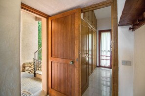 A wooden door leading to a room with a tiled floor and a stone wall outside. - GuestHost - Dreamy Sea View with Pool and Parking (Olbia)
