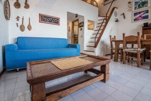 A living room with a blue sofa, wooden coffee table, and a staircase.