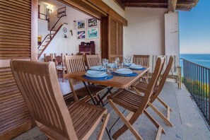 A wooden table set for four with chairs, a staircase, and a view of the sea. - GuestHost - Dreamy Sea View with Pool and Parking (Olbia)