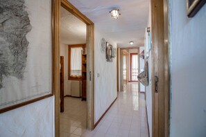 A hallway with a map, wooden doors, and a tiled floor.