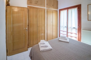 A bedroom with a bed, a wardrobe, and a window with curtains.