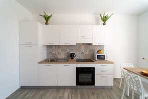 Una cocina moderna con armarios blancos, encimera de madera, microondas y dos plantas en macetas.