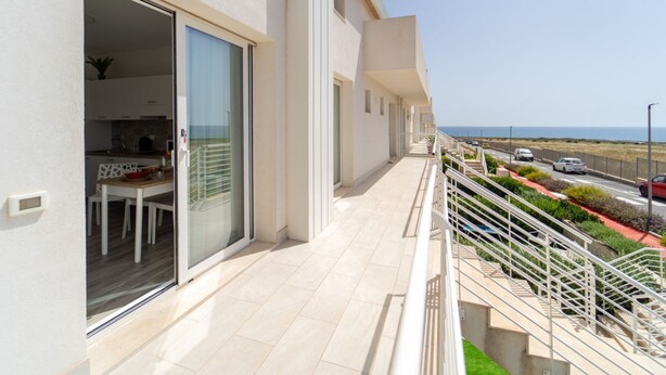 Ein modernes Gebäude mit Balkon, Essbereich und Meerblick.