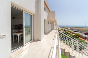 A modern building with a balcony, a dining area, and a view of the sea.