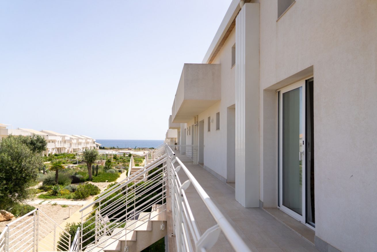 A balcony with a view of the sea and a resort complex.