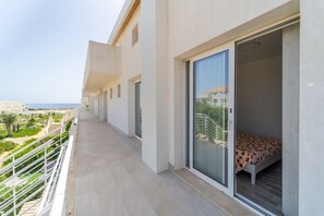 Ein Balkon mit einem Bett, einer Glastür und Blick aufs Meer.
