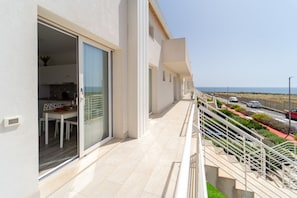 Un edificio moderno con balcón, comedor y vista al mar.
