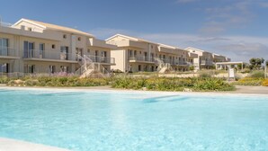 Ein Hotel mit mehreren Balkonen, einem Schwimmbad und einem angelegten Garten.