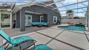 A covered outdoor area with a pool, seating, and lounge chairs.