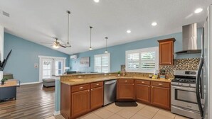 A modern kitchen with wooden cabinets, a stainless steel refrigerator, and a built-in oven.