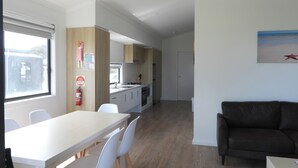 A modern kitchen with white cabinets, a dining area with a table and chairs, and a living room with a sofa. - BIG4 Kingston Foreshore Holiday Park (Kingston SE)