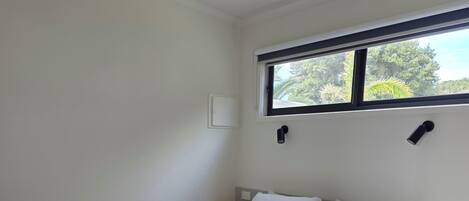 A bedroom with a bed, a ceiling fan, a window, and a nightstand.
