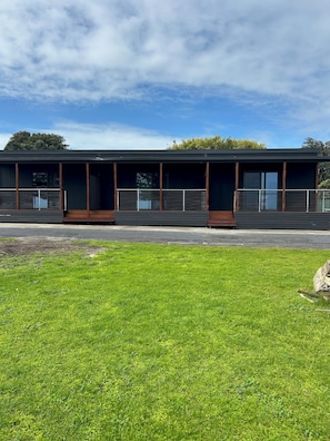 A modern building with large windows and a flat roof, surrounded by a well-maintained lawn.