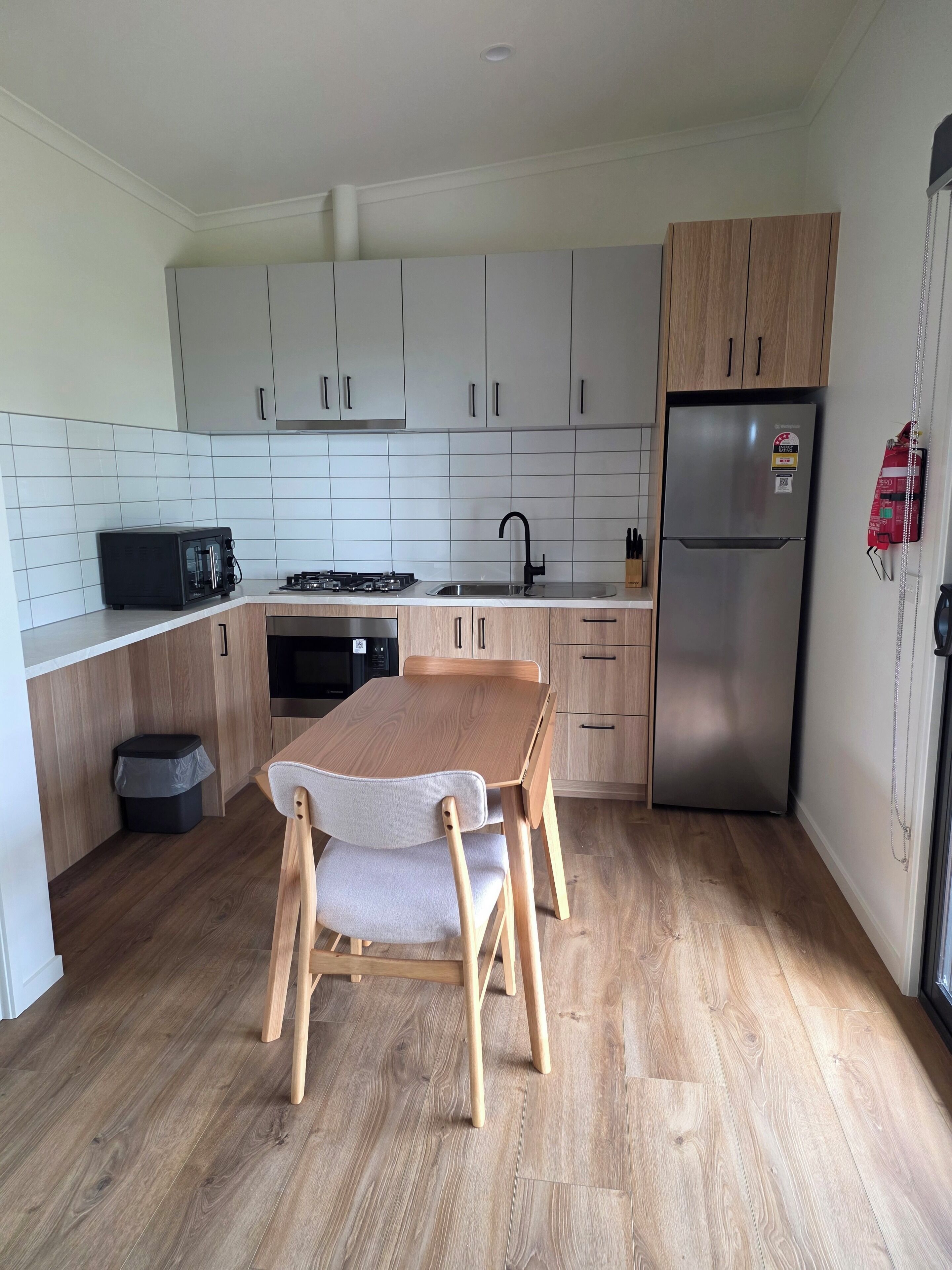 A modern kitchen with a dining table, chairs, a refrigerator, a stove, and cabinets.