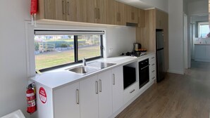 A modern kitchen with white cabinets, a stainless steel sink, and a gas stove. - BIG4 Kingston Foreshore Holiday Park (Kingston SE)