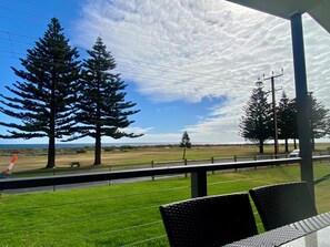 Un balcon donnant sur un champ verdoyant, des arbres et un ciel dégagé.