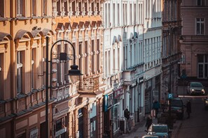 A street view with buildings featuring classic architecture, a street lamp, and parked cars.